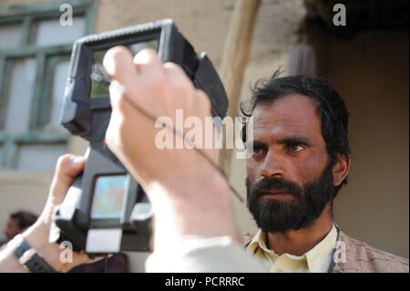 Un membre de la Force d'opérations spéciales de la coalition utilise un scanner biométrique sur un villageois de Sayadabad, district de la province de Wardak. Les commandos de l'Armée nationale afghane, assistée par les forces spéciales de la coalition, a dirigé une opération de compensation jour et a effectué une patrouille dans Saydabad unilatérale. Banque D'Images