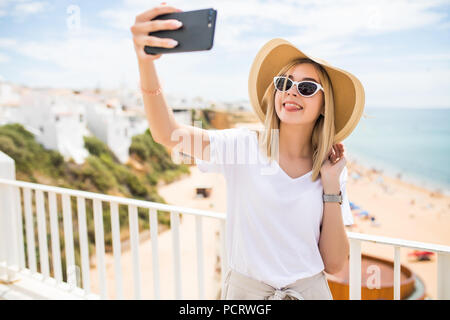 Les jeunes qui voyagent woman holding téléphone faire contre selfies sur la mer. Banque D'Images