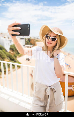 Les jeunes qui voyagent woman holding téléphone faire contre selfies sur la mer. Banque D'Images