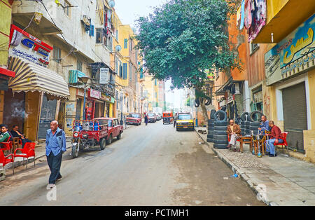 Alexandrie, Egypte - le 18 décembre 2017 : l'étroite rue du quartier Karmouz pauvres avec les tables des salons locaux, où les visiteurs fumer la chicha et drin Banque D'Images