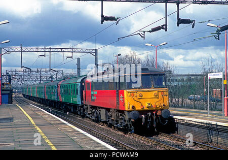 Une classe 86 AC electric locomotive Nombre 86430 avec la marque Pilkington un râteau en remorque se dirige vers le sud à travers la herse et Wealdstone avec une charte de football le 10 avril 1994. Banque D'Images