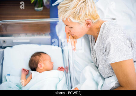 À la mère avec l'amour à son nouveau-né garçon encore dans l'hôpital Banque D'Images