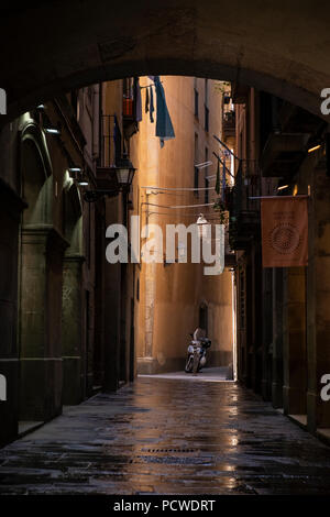 Dalles humides dans une vieille ruelle avec scooter garé dans une tache de lumière, Barri Gotic, le quartier gothique, Barcelone, Espagne Banque D'Images