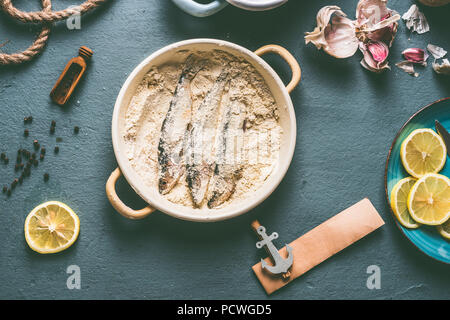 Sardines à la mie de pain sur la table de cuisine avec des ingrédients de base : citron, ail et herbes pour la cuisine de fruits de mer savoureux. Préparation Cuisson des poissons Banque D'Images