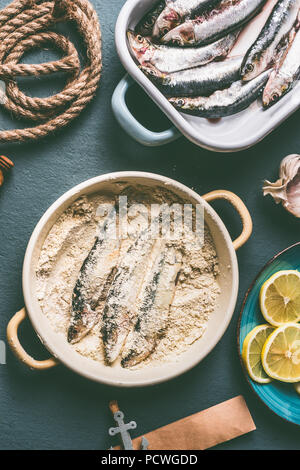 Enduire les sardines avec des miettes de pain sur la table de cuisine avec des ingrédients de base : citron, ail et herbes pour la cuisine de fruits de mer savoureux. Préparation Cuisson o Banque D'Images