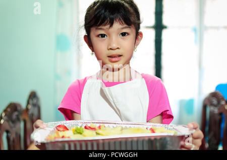 Une jeune fille des tâches mixtes salade de fruits qu'elle avait préparé. Banque D'Images