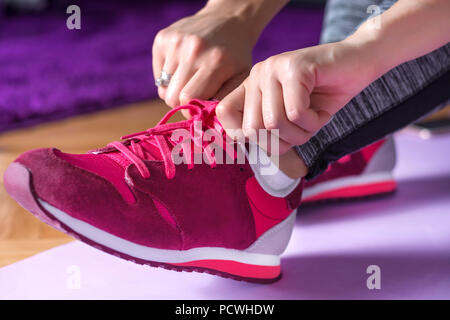 Jeune fille jambes avec red sneakers préparation au travail à la maison sur le tapis de yoga violet ou d'adaptation. Sport et loisirs concept. Close up portrait Banque D'Images