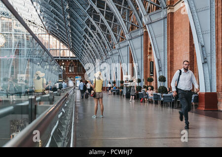 Femme non identifiée dans un haut jaune à parler au téléphone à l'intérieur de St Pancras Station, London, UK. Banque D'Images