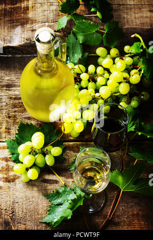 Fond de vin. Blanc et vin rouge dans les verres, bouteille, raisins sur fond vintage, vin concept. Banque D'Images