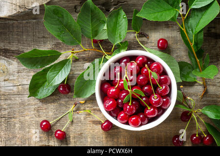 Les cerises fraîches dans un bol en céramique sur une table en bois. Le concept de nutrition santé ou la désintoxication. Vue supérieure de la télévision mise de fond. Banque D'Images