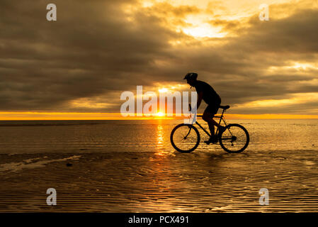 Seaton Carew, County Durham, Angleterre. United Kingdom. 4 Août, 2018. Météo France : une des promenades en vélo de montagne le long de la plage au lever du soleil le samedi comme les nuages d'une nuit claire à Seaton Carew sur la côte nord-est. Banque D'Images