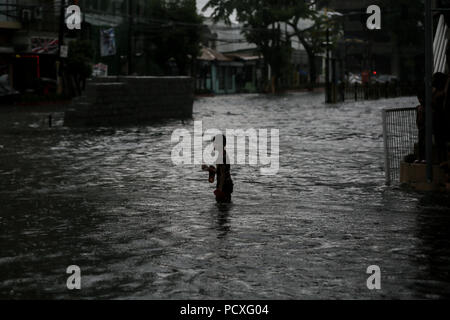 Aux Philippines. 4 Août, 2018. Un garçon se tient sur une rue inondée après une forte pluie à Manille, Philippines, le samedi. Le 4 août 2018. Les précipitations sont attendues dans certaines régions de Luzon et de la région métropolitaine de Manille en raison d'orages violents portés par la mousson du sud-ouest. Credit : Basilio Sepe/ZUMA/Alamy Fil Live News Banque D'Images