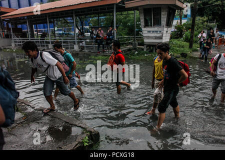 Manille, Philippines. 4 Août, 2018. Les gens traverser une voie ferrée inondée après une forte pluie à Manille, Philippines, le samedi. Le 4 août 2018. Les précipitations sont attendues dans certaines régions de Luzon et de la région métropolitaine de Manille en raison d'orages violents portés par la mousson du sud-ouest. Credit : Basilio Sepe/ZUMA/Alamy Fil Live News Banque D'Images