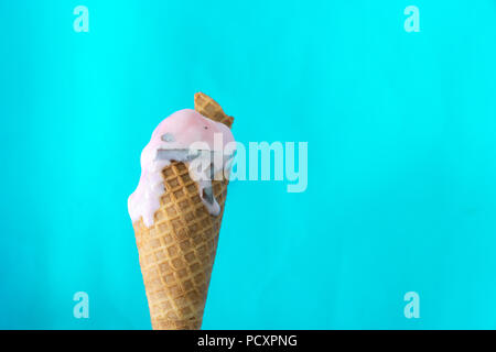 Cornet de crème glacée fondue sur fond bleu menthe Banque D'Images