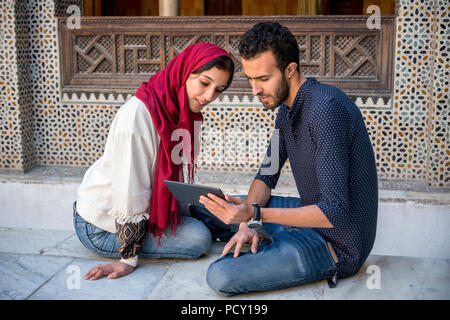 Jeune musulman en couple smiling relation tout en travaillant sur le comprimé dans l'arabe traditionnelle Banque D'Images