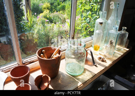 Bouteilles, bocaux en verre et des pinces à linge dans la fenêtre d'un Vieil abri de jardin, Angleterre, Royaume-Uni - John Gollop Banque D'Images