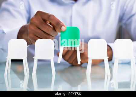 Businessman Holding siège vert de la chaises blanches Banque D'Images