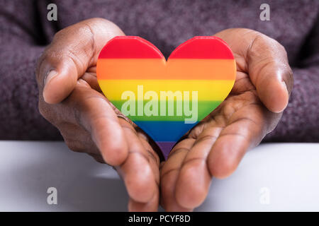 Close-up of Man's Hand Holding coeur peint à rayures colorées Banque D'Images