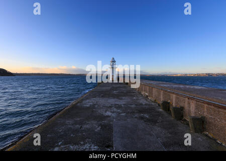 Un petit phare blanc à l'extrémité du brise-lames à Brixham Harbour, Brixham, Devon, se détache sur un ciel bleu clair Banque D'Images