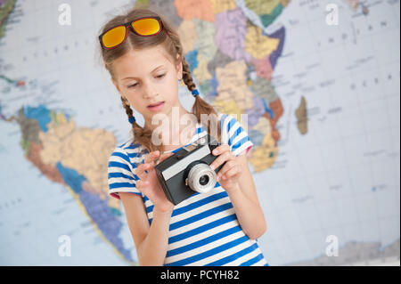 Peu intéressées caucasian girl étudiant caméra dans les mains sur l'arrière-plan du monde Banque D'Images