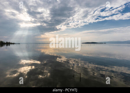 Parfaitement symétrique et vue spectaculaire d'un lac, avec des nuages, le ciel et les rayons du soleil reflétant sur l'eau Banque D'Images