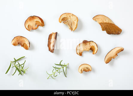 Tranches de champignons séchés et de romarin sur fond blanc Banque D'Images