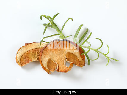 Tranches de champignons séchés et de romarin frais sur fond blanc Banque D'Images