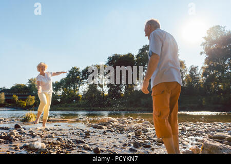 Funny senior couple jouant avec de l'eau à la rivière dans une journée ensoleillée Banque D'Images