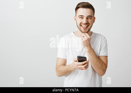 Guy lire blague de l'internet de Rire passer du temps amusé et diverti tout sourire à toucher l'appareil photo et barbe de plisser la joie Banque D'Images