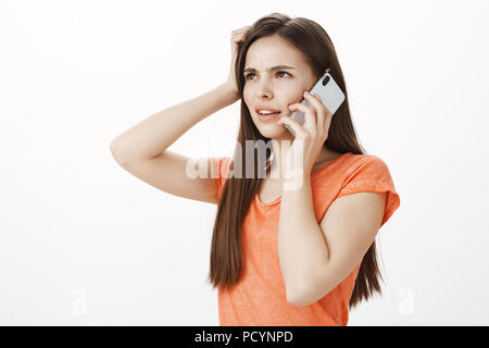 Pas sûr amie essaie de penser ce qu'il faut répondre. Studio Portrait de femme attrayante concernés en difficulté demi-permanent mis sur fond gris, sc Banque D'Images