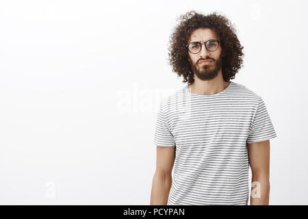 Sérieux suspects hispaniques dans le quartier branché d'attrayants guy lunettes, levée de doute et de sourcil fixant le strict et précis à l'attention de l'écoute, l'appareil photo Banque D'Images