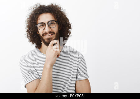 Belle idée, vous m'intriguaient. Portrait of handsome man smart intéressées avec barbe et cheveux bouclés dans des verres, et curieusement rubbin smiling Banque D'Images