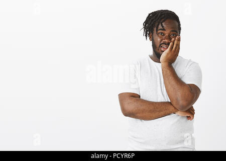 Portrait de jeune femme africaine impressionné choqué en t-shirt blanc, tenant sur palm et contemplant avec mépris face à l'appareil photo, d'être impressionné par la Banque D'Images