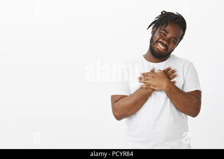 Portrait de heureux mignon dodu africains-américains guy avec barbe et moustache, tilting head et souriant de mots réconfortants, holding palms sur la poitrine Banque D'Images