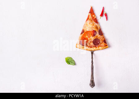 Morceau de pizza au pepperoni, avec saucisses et tomates sur fond blanc. Banque D'Images