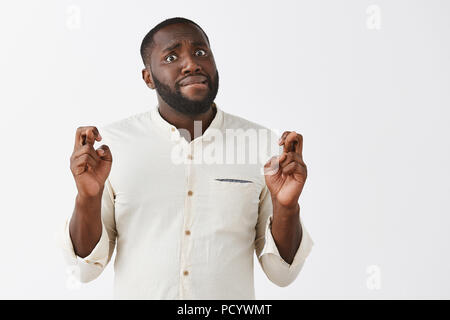 L'homme préoccupé par faire face, croisant les doigts, espérant pour de bons résultats. Portrait de beau nerveux à la peau sombre moderne entrepreneur, mordre la lèvre, st Banque D'Images