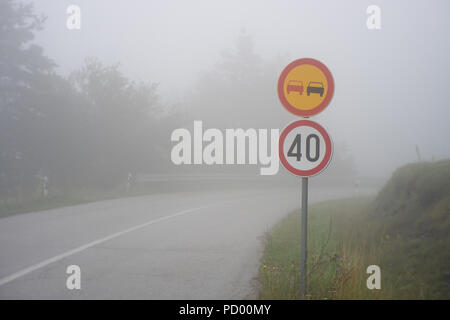 Le panneau de signalisation indiquant la limite de vitesse sur route misty avec une faible visibilité. Route à travers la forêt de brouillard Banque D'Images