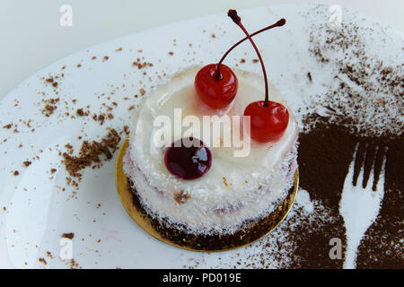 Vue de dessus du délicieux gâteau au chocolat blanc à la noix de coco et des cerises dans une assiette et une fourchette contours décoration cacao Banque D'Images