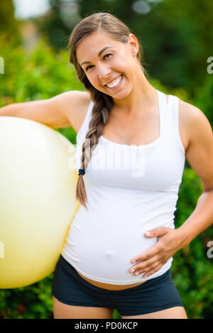 Smiling pregnant woman Touching Belly tout en maintenant l'exercice Bal Banque D'Images