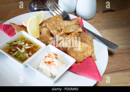 Un pub anglais/restaurant entree plat de poulet rôti à la peau avec de la mayonnaise et l'ail, le paprika et trempettes salsa de tomate garnie de citron frais Banque D'Images