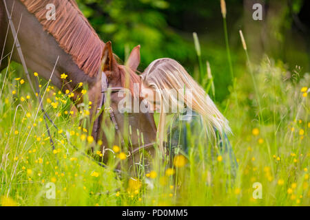 Heureux femme assise dans la prairie avec son cheval arabe Banque D'Images