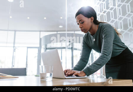 Young woman standing by table de conférence et de travail sur ordinateur portable. La préparation d'une proposition d'affaires des femmes avant une réunion en salle du Conseil. Banque D'Images