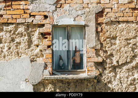 Les nains de jardin décoratif dans une fenêtre d'un bâtiment abandonné dans un village de l'Allemagne Banque D'Images