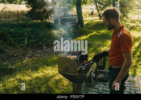 Photo d'un homme de race blanche qui travaille le gril pendant un barbecue Banque D'Images