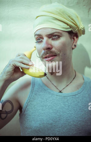 Portraits créatifs d'un jeune homme blanc avec un turban jaune, curly moustache et une barbiche, debout devant un mur avec des ombres en diagonale. Banque D'Images