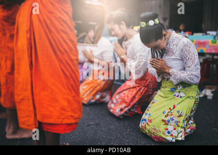 Femme thaïlandaise rendent hommage à un moine bouddhiste au matin. Banque D'Images