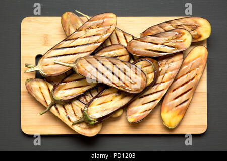 Aubergines grillées sur conseil de bambou sur une table en bois sombre, vue du dessus. Libre. Banque D'Images