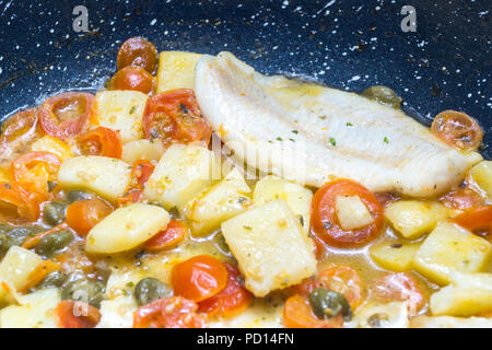 Cabillaud cuit dans une casserole, avec de la tomate, les pommes de terre et les câpres Banque D'Images