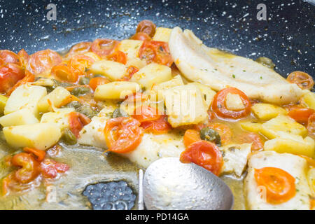 Cabillaud cuit dans une casserole, avec de la tomate, les pommes de terre et les câpres Banque D'Images