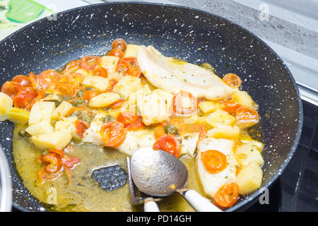 Cabillaud cuit dans une casserole, avec de la tomate, les pommes de terre et les câpres Banque D'Images